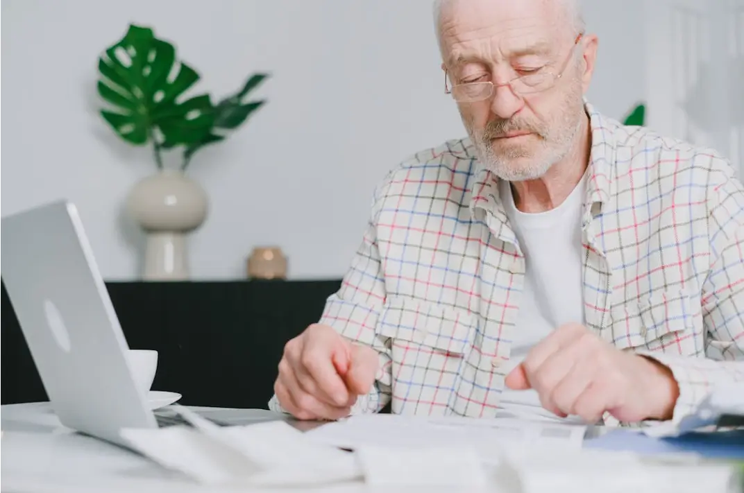 Middle aged man with computer and paperwork, representing assessing and planning his estate.