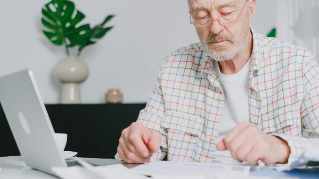 Middle aged man with computer and paperwork, representing assessing and planning his estate