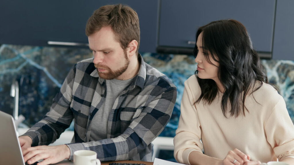 Couple reviewing financial documents on a laptop, discussing financial planning