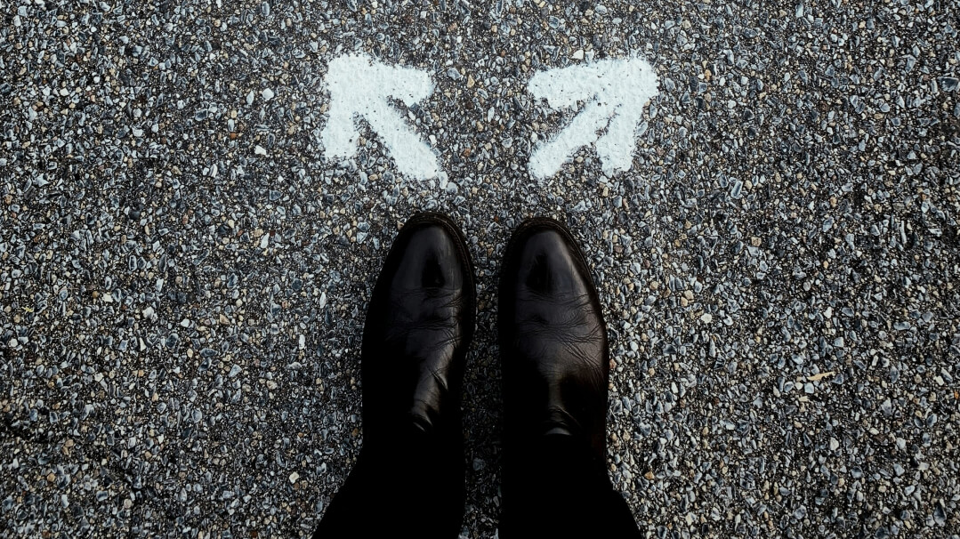 Person standing at a forked path marked by arrows, symbolising choosing well in financial advice decisions