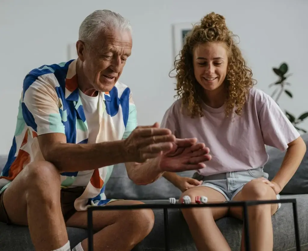 Older man and younger woman sitting together at home, sharing a moment that reflects intergenerational planning and connection.