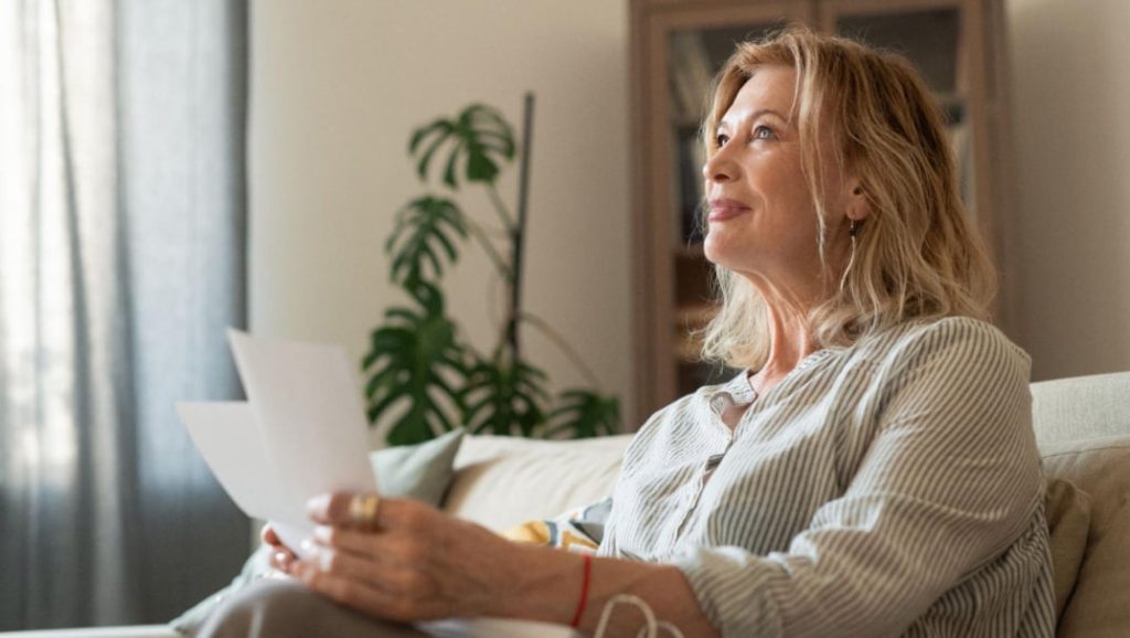 Woman reviewing household bills in her loungeroom, reflecting everyday financial habits and money management
