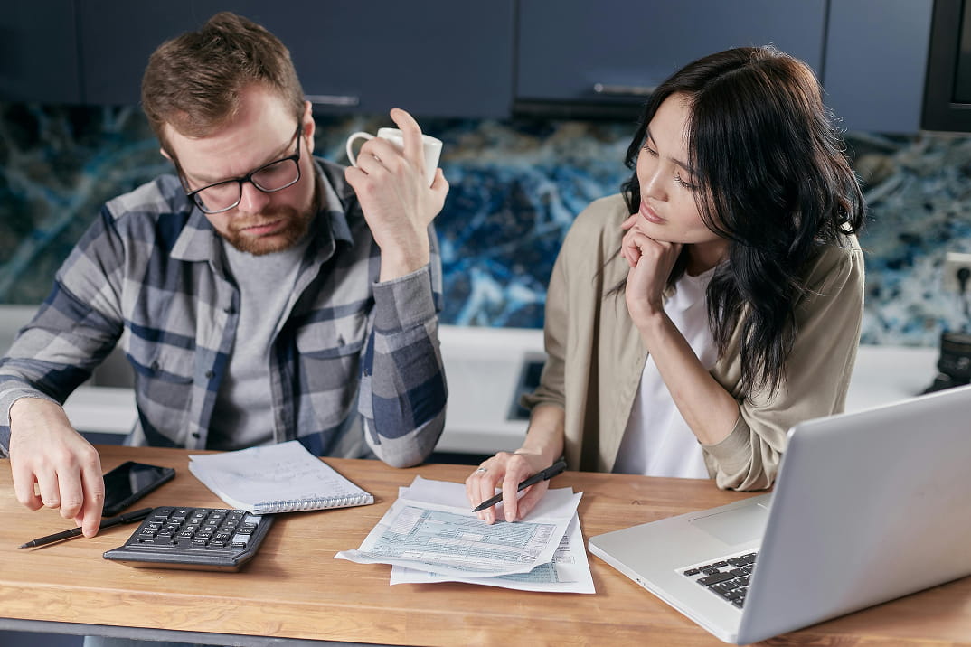 Couple reviewing household finances and calculating expenses at home