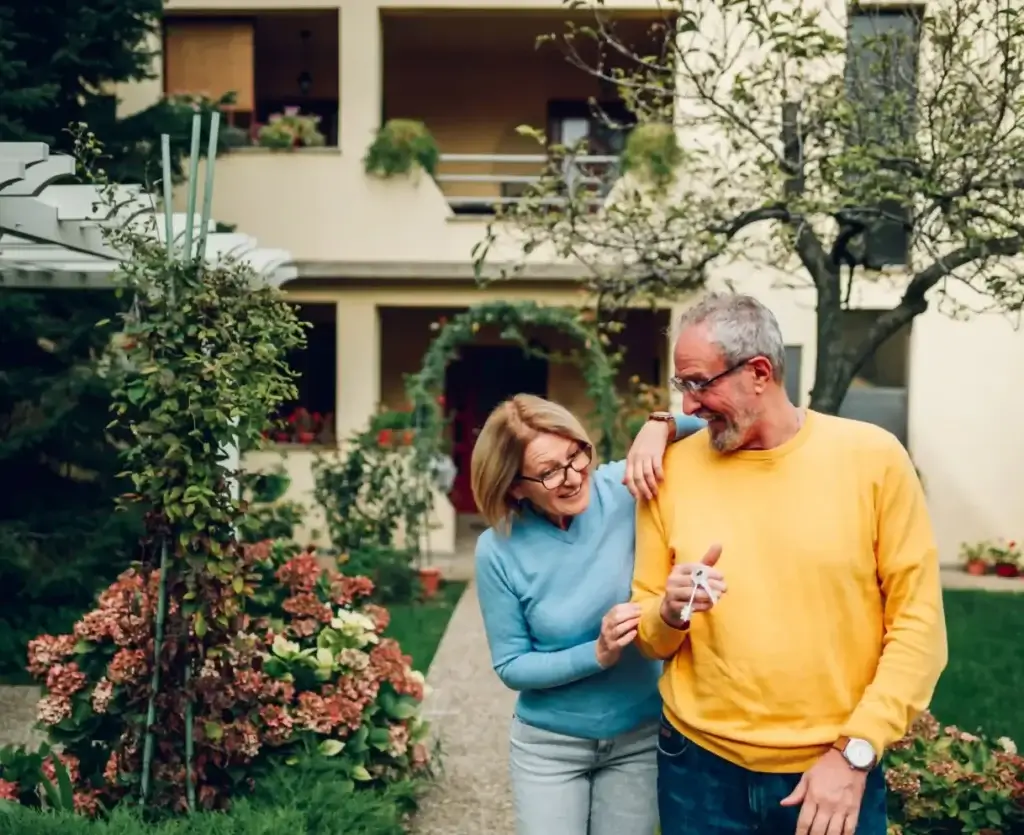 Older couple walking through their garden at home, talking together about life plans and the transition into retirement.